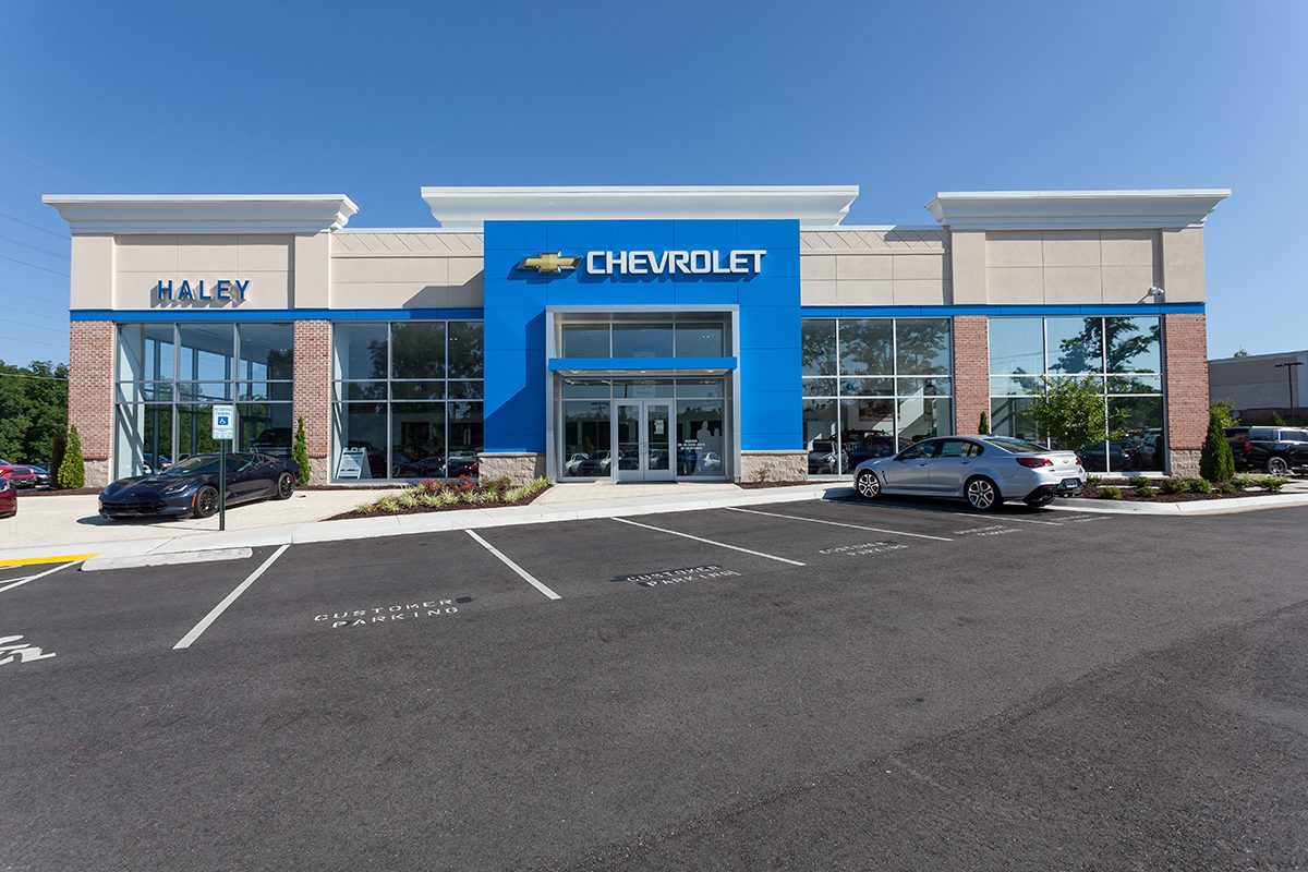 Exterior of a modern Chevrolet car dealership with parked cars and clear skies