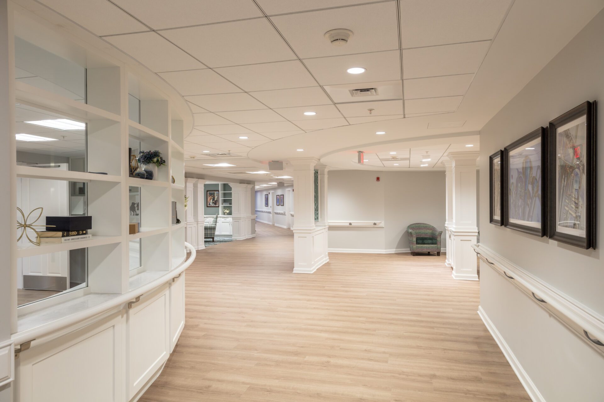 Bright, modern corridor with wooden floors, white trim, and framed art on walls