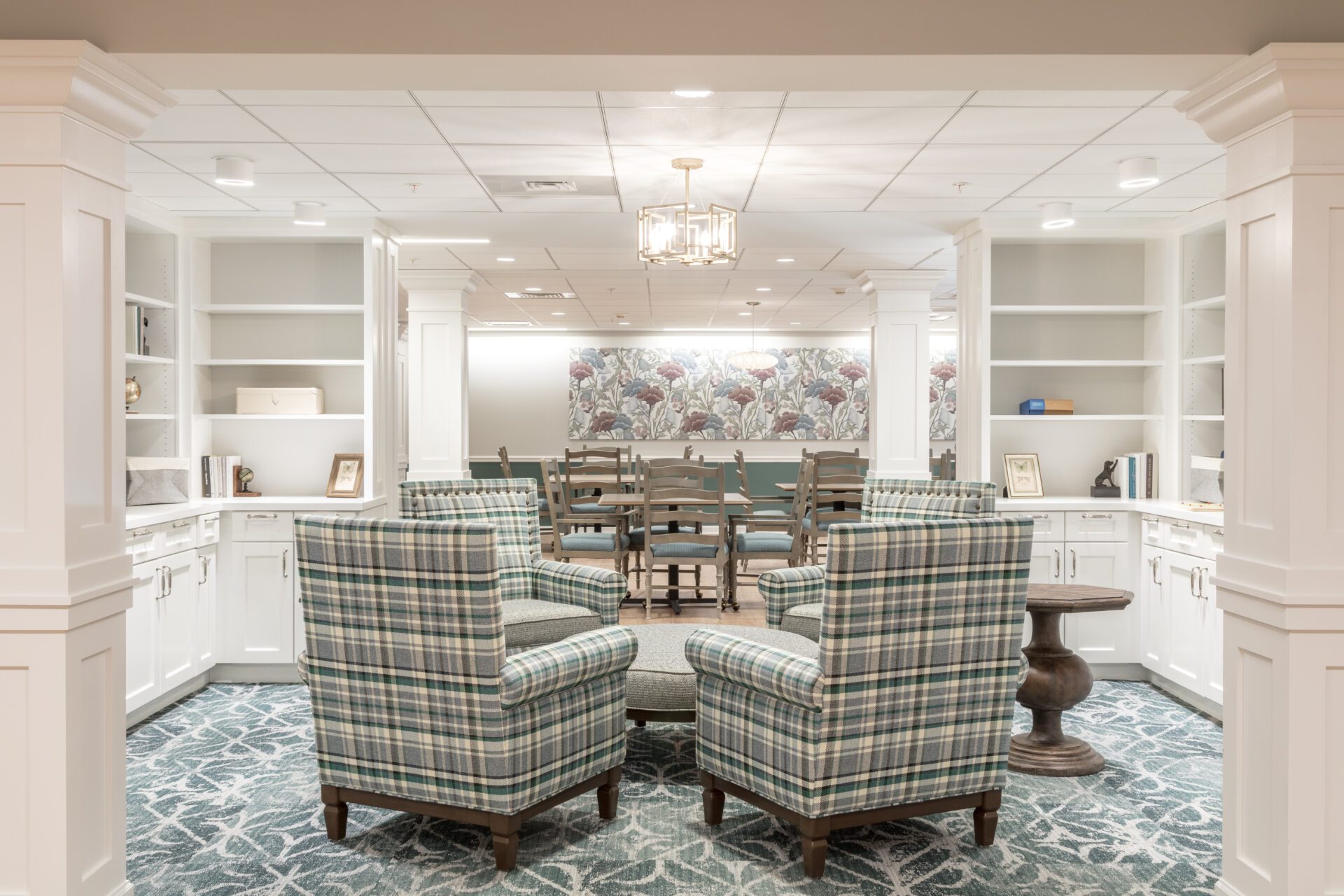 Elegant interior of a well-lit library with plaid armchairs and white bookshelves