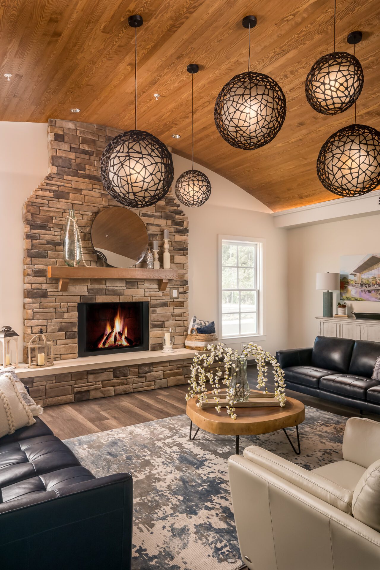 Cozy living room with fireplace, wooden ceiling, unique pendant lights, and modern furniture