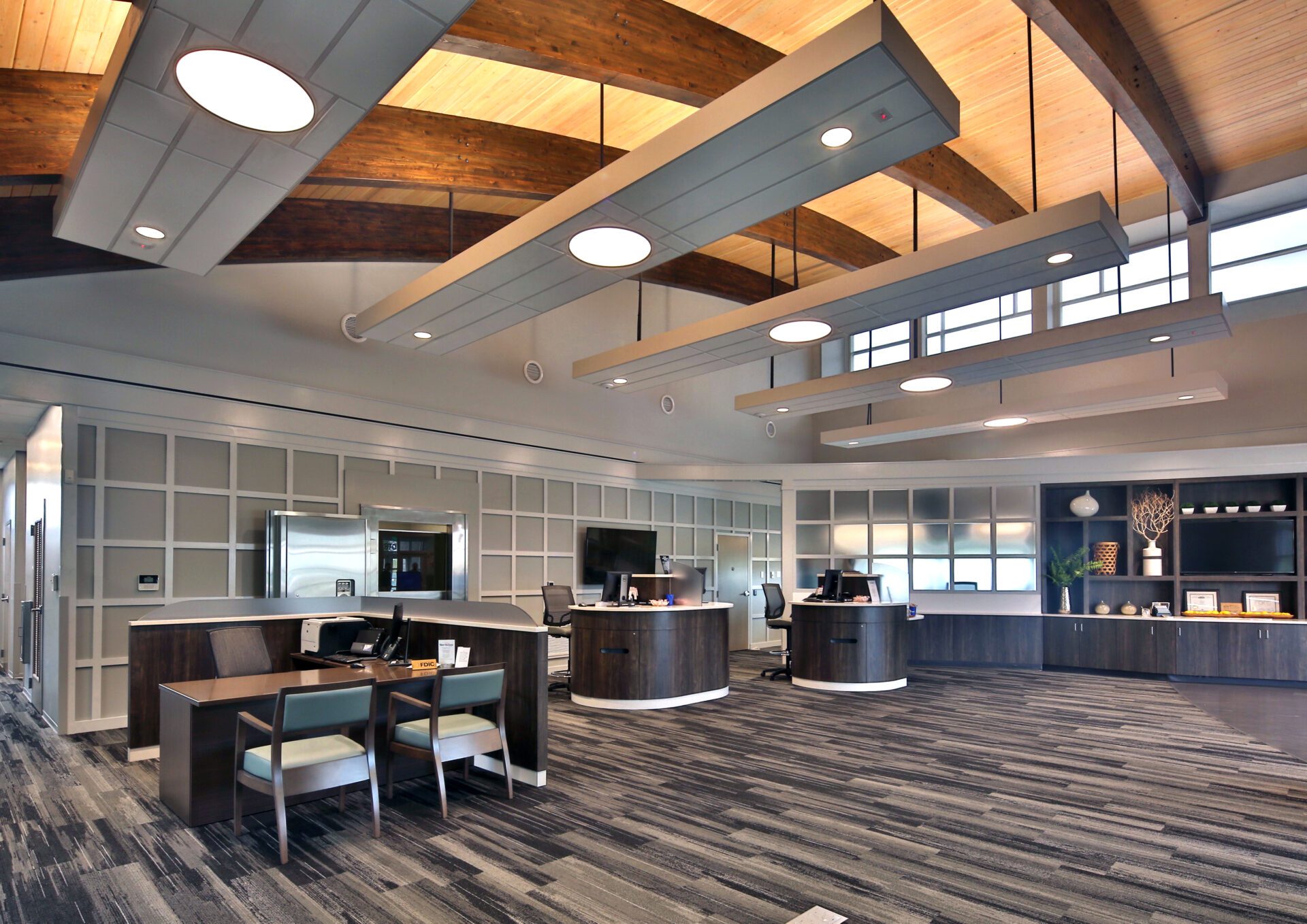 Modern office lobby with two reception desks, wooden accents, and stylish lighting fixtures