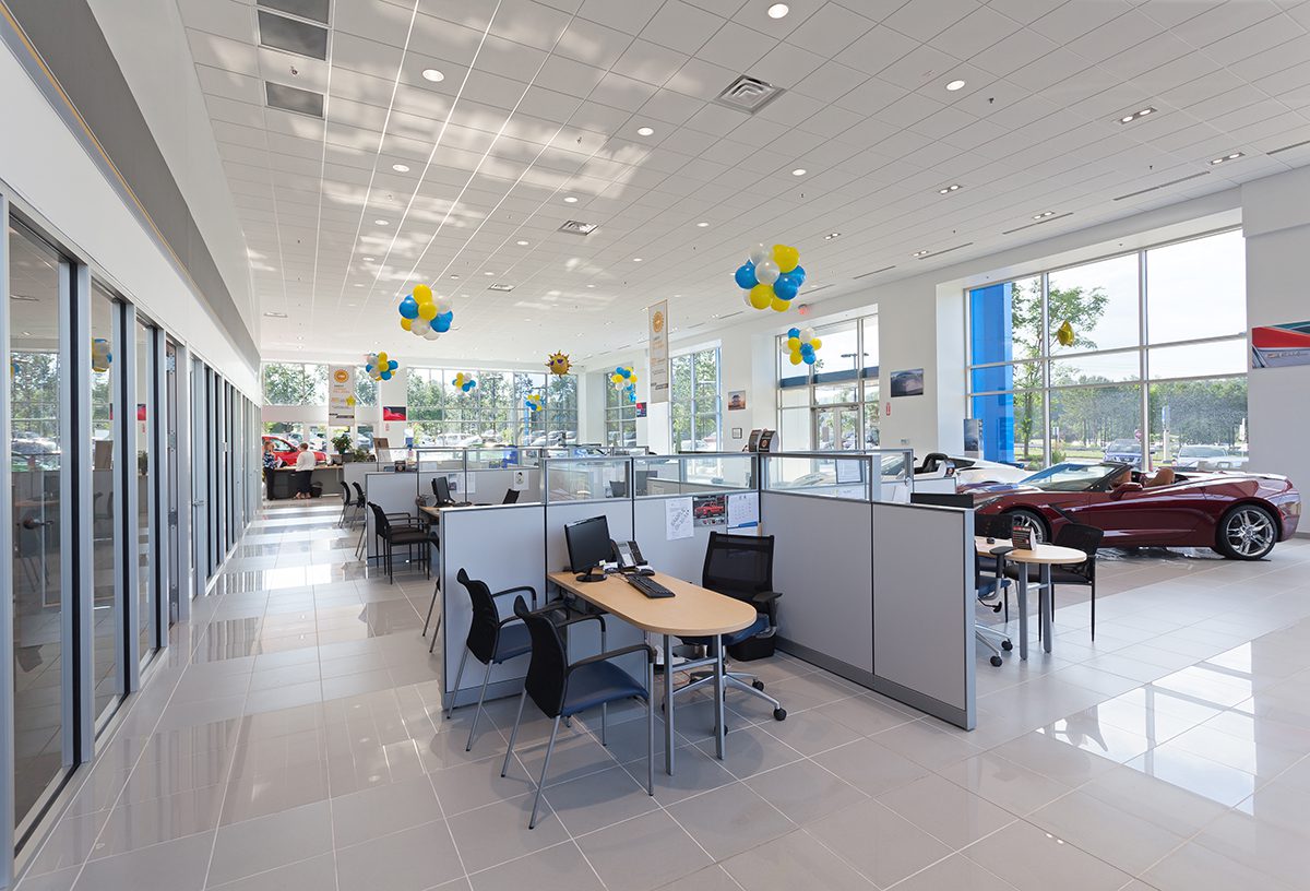 Bright car dealership interior with desks, decorations, and a convertible car