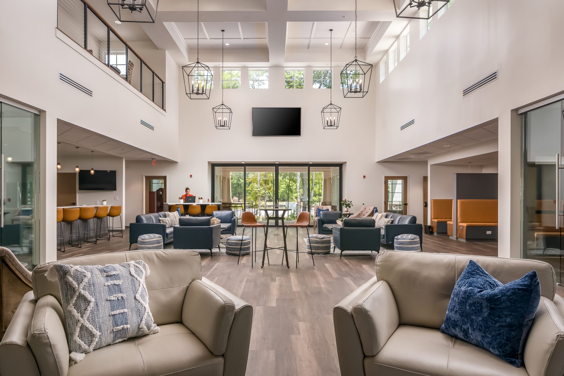 Modern lobby interior with sofas, chairs, pendant lights, and large windows