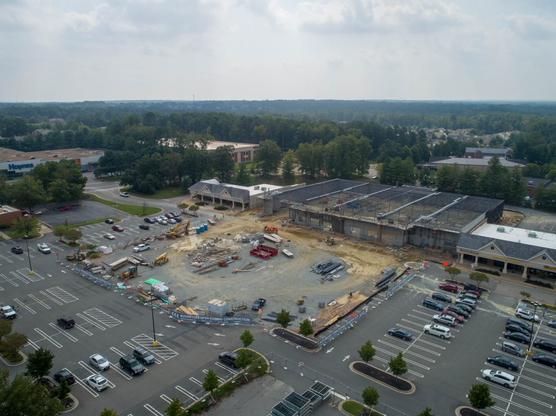 Aerial view of a construction site near a parking lot and surrounding buildings