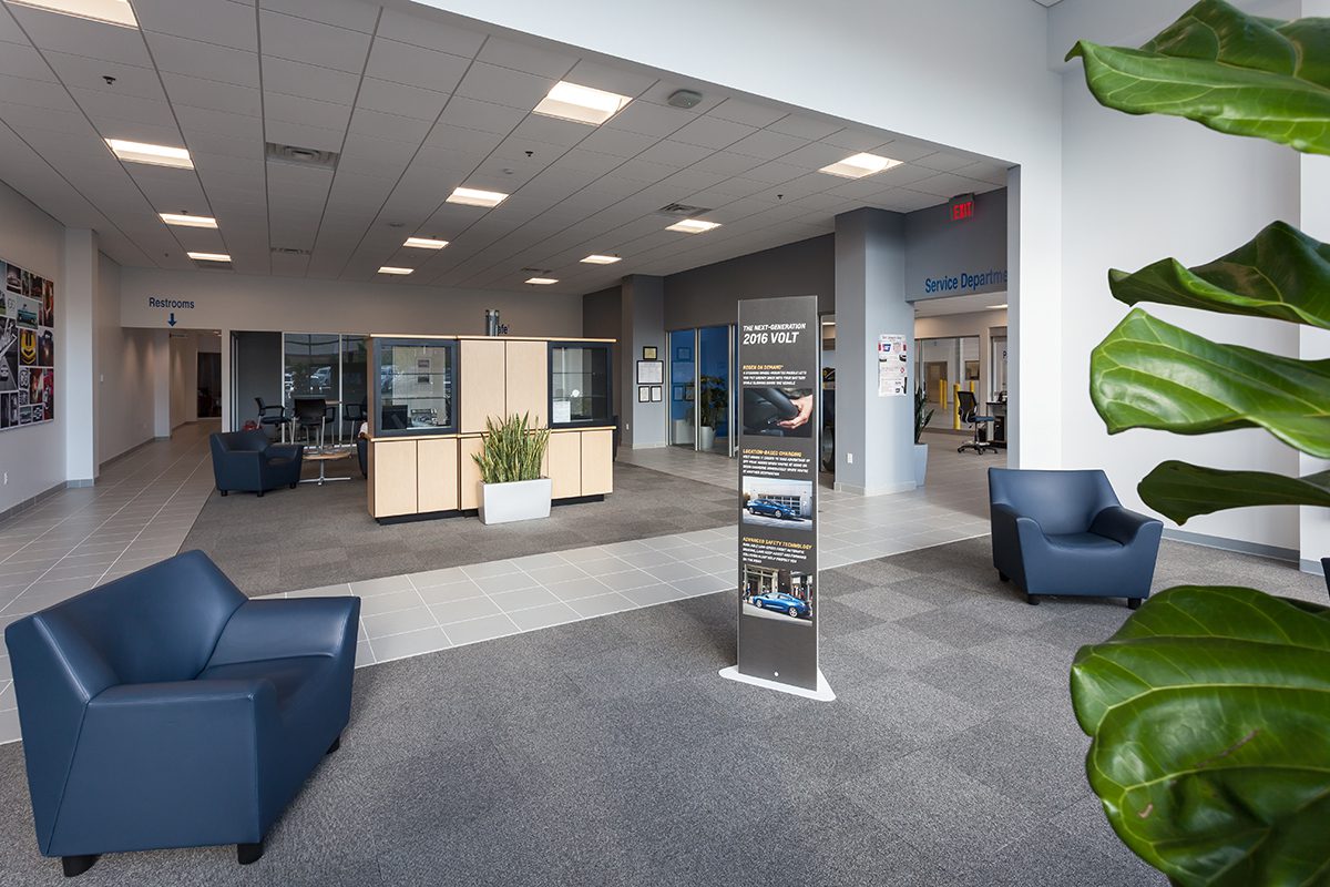 Modern dealership waiting area with chairs, informational stands, and indoor plants