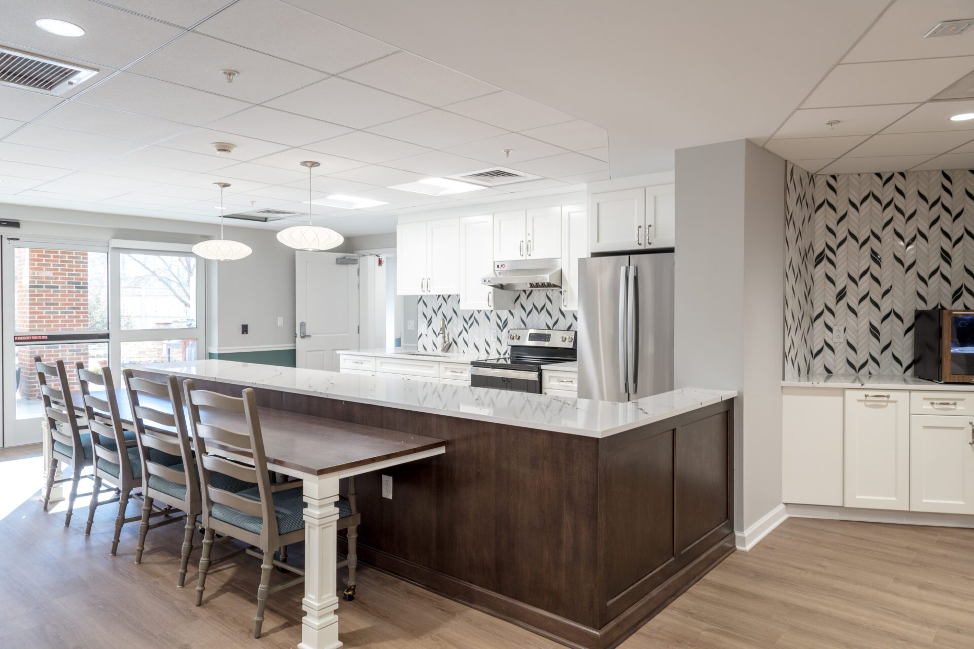 Modern kitchen interior with a bar-style dining area, stainless steel appliances, and herringbone backsplash