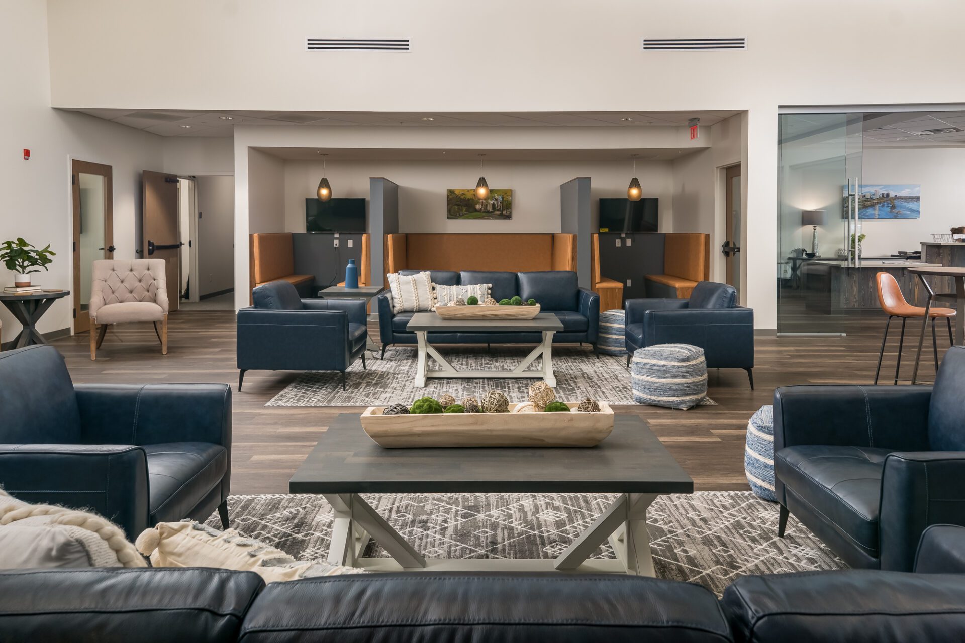 Modern lounge area with blue and beige seating, accent lighting, and a central wooden table