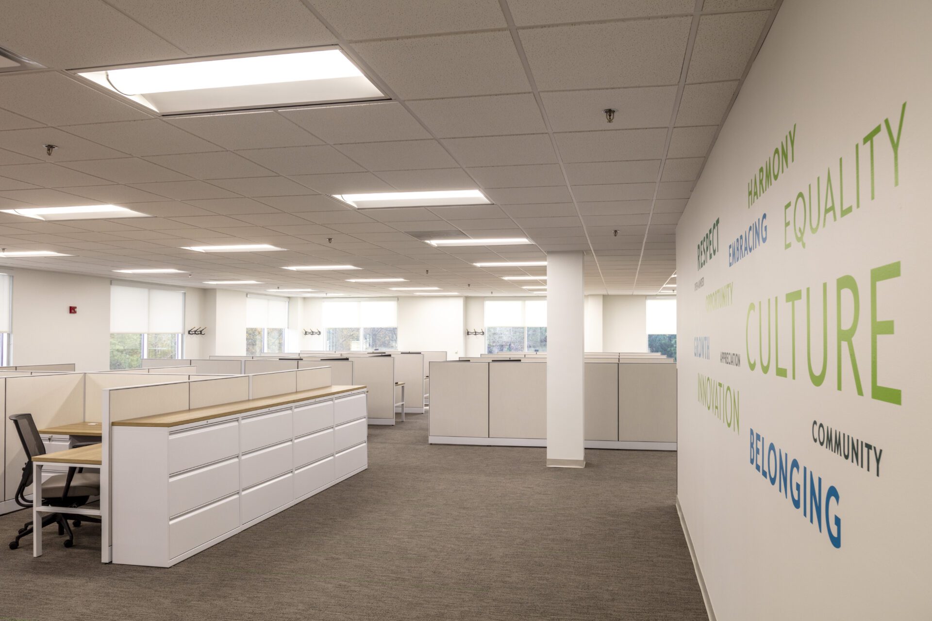 Bright modern office with desk and chair, viewed through glass door