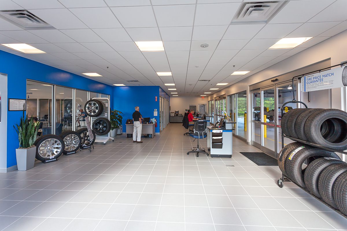 Bright car service center interior with tire displays, desks, and employees