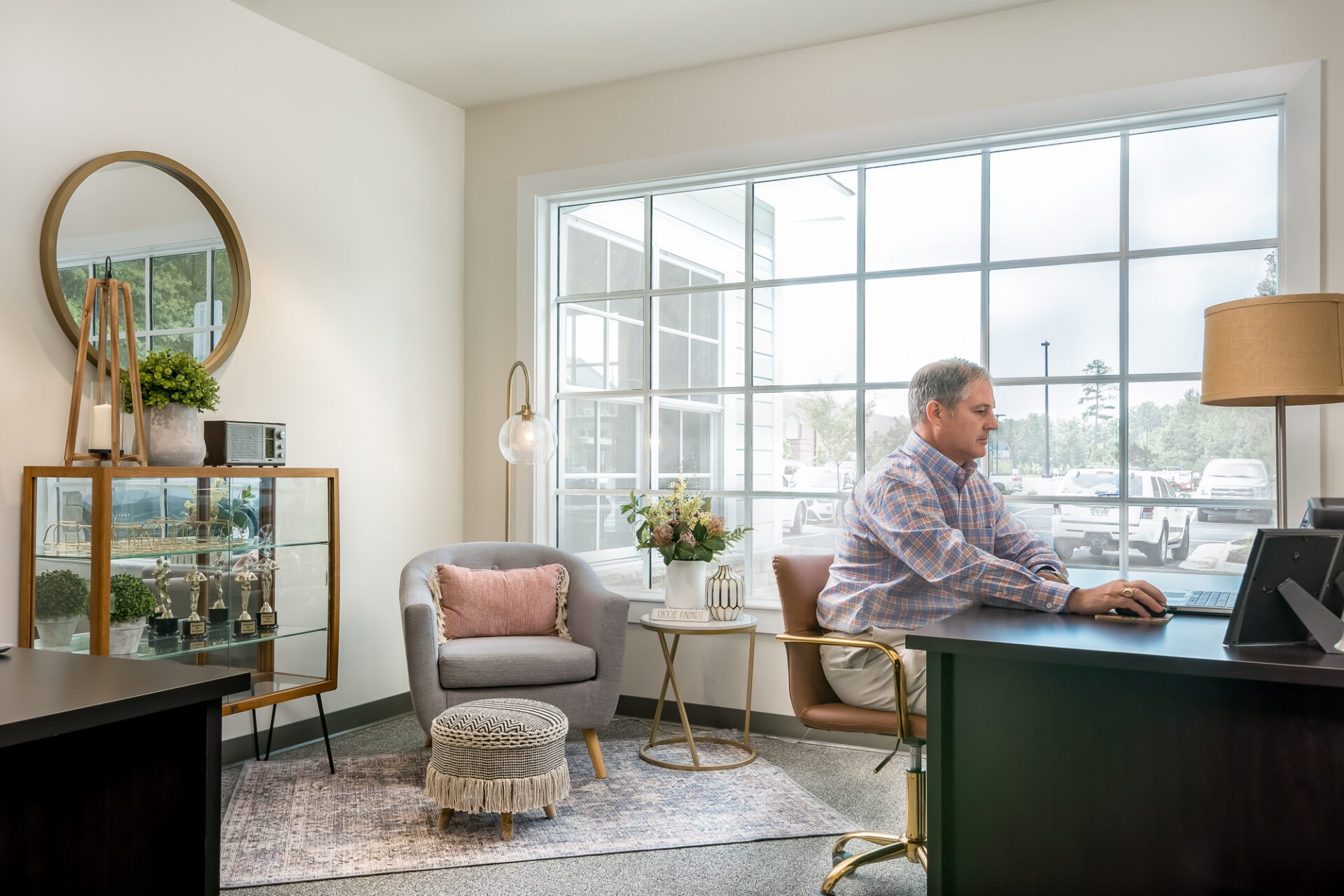 Person working at a desk in a modern office with large windows and stylish furnishings