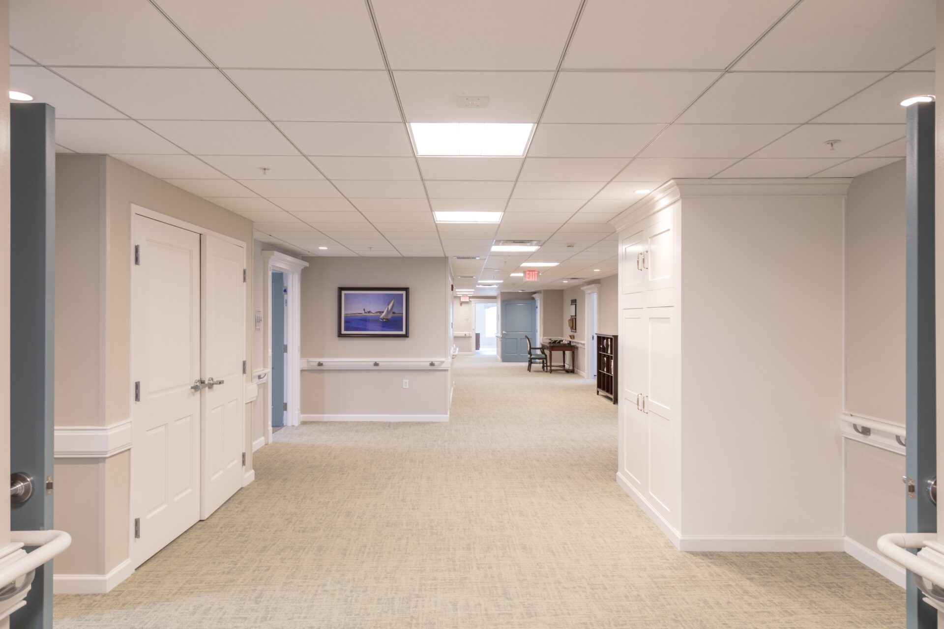 Bright, modern office hallway with doors and framed artwork on walls